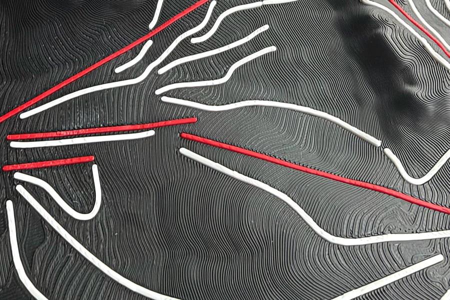 Close-up of raised white run lines and red lift lines over the fine printed layer lines of black Alpental terrain.