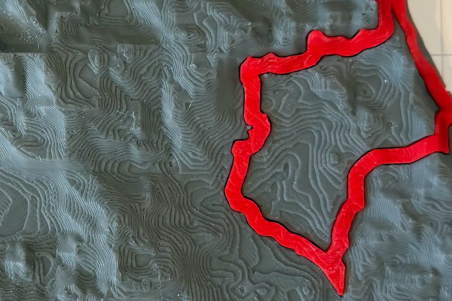 Close-up of grey 3D-printed contour layers on a Brazil relief map, with the São Paulo state outline raised in red.