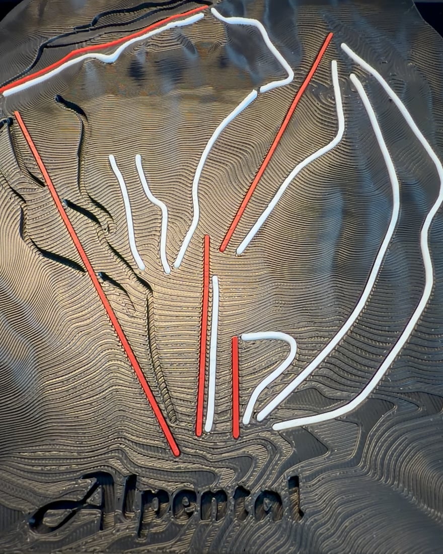 A black Alpental relief with raised white runs and red lift lines fitted into their channels across layered terrain.